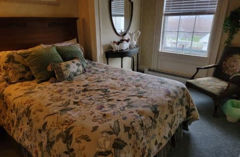 Bedroom with queen bed with floral comforter and window overlooking mountains